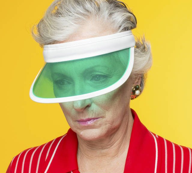 Frau mit grüner Schildkappe vor gelbem Hintergrund