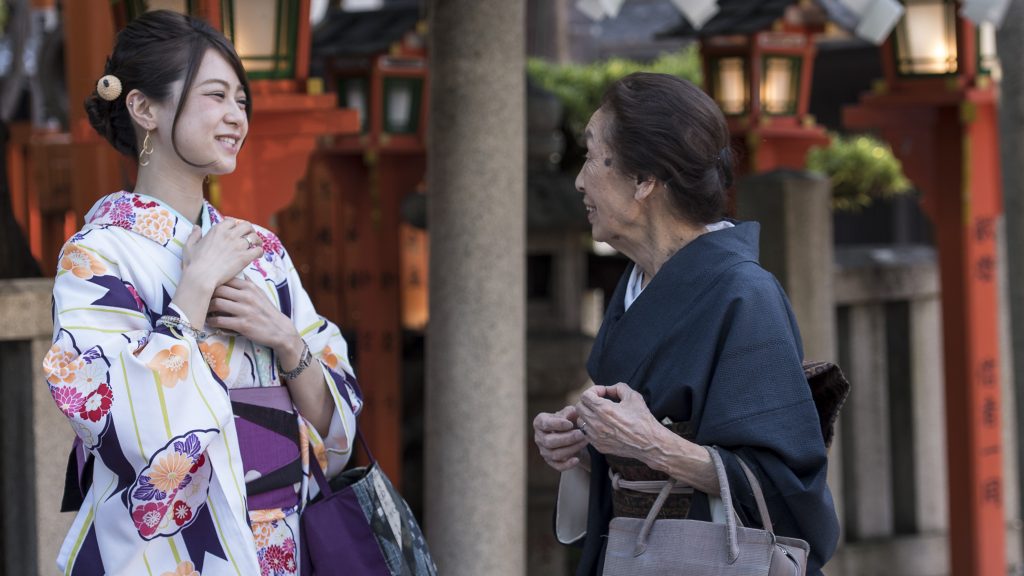 Begegnung in Japan: Zwei in traditionelle Kimonos gekleidete Frauen unterhalten sich bei der Gion Tatsumi Brücke.